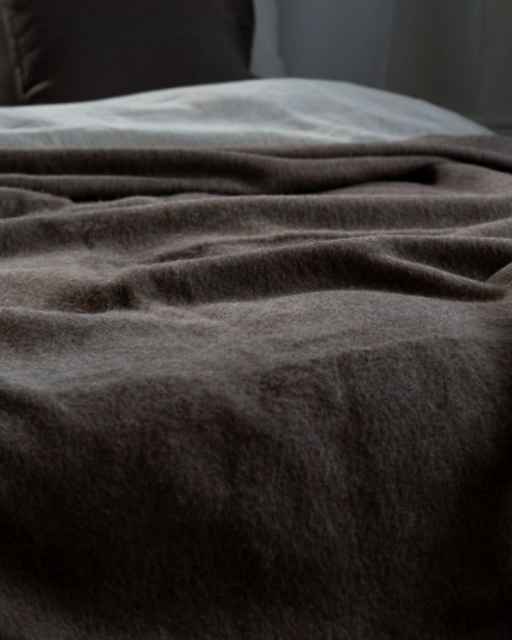 Dark gray blanket draped over a surface with a neutral background