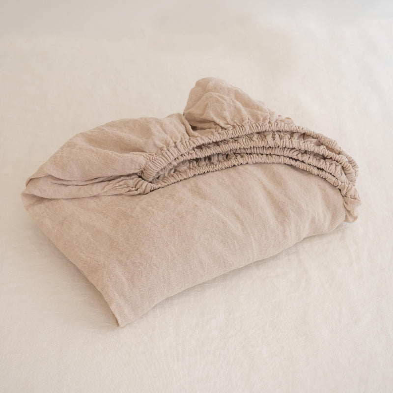 Folded nude linen sheet on a white background