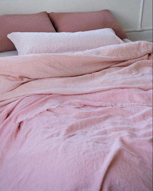 Pink textured blanket and pillows on a bed in a bedroom setting