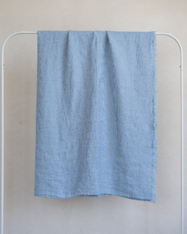 Blue towel hanging on a white rack against a plain wall