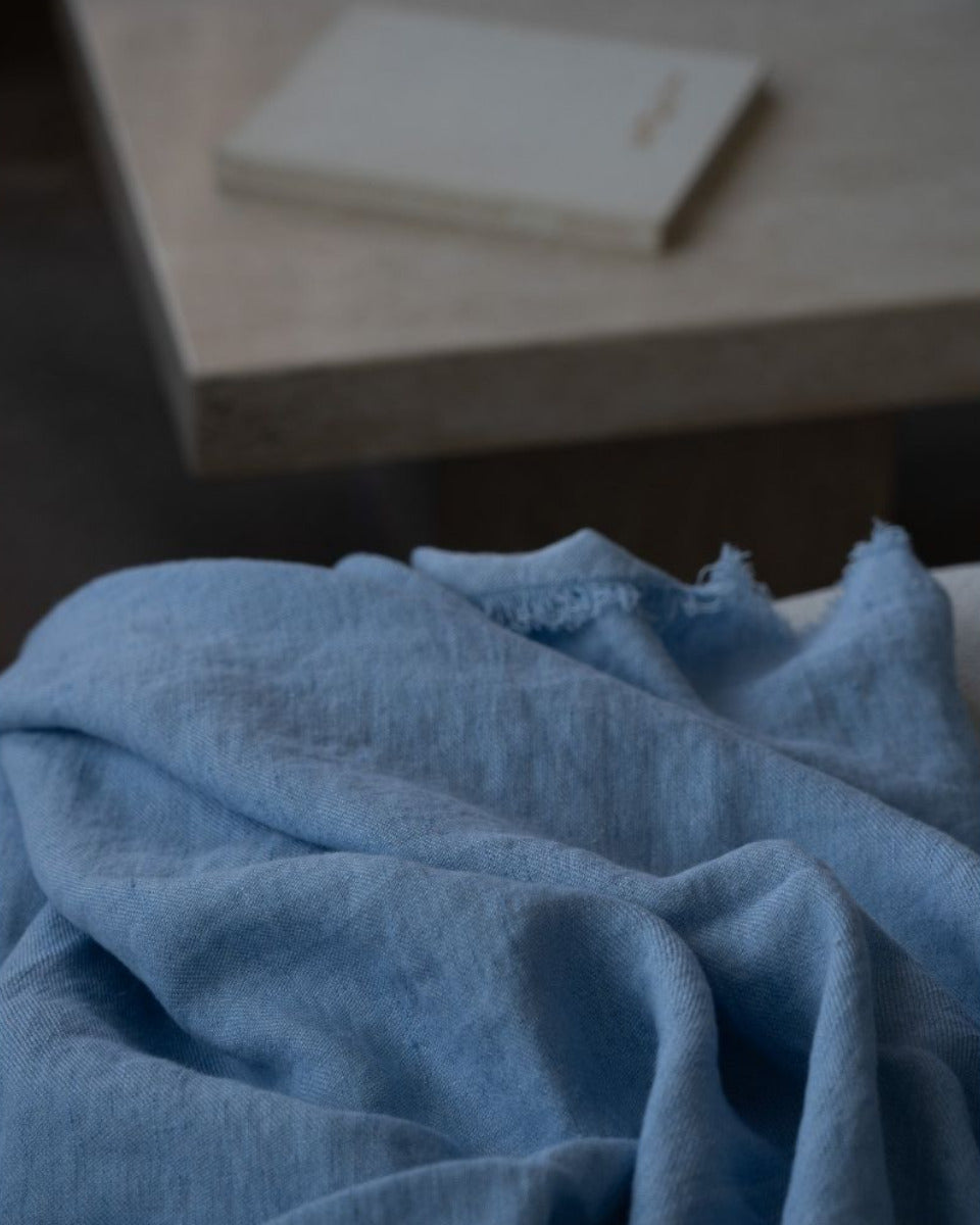Azure blanket with a blurred background of a wooden surface and white object.