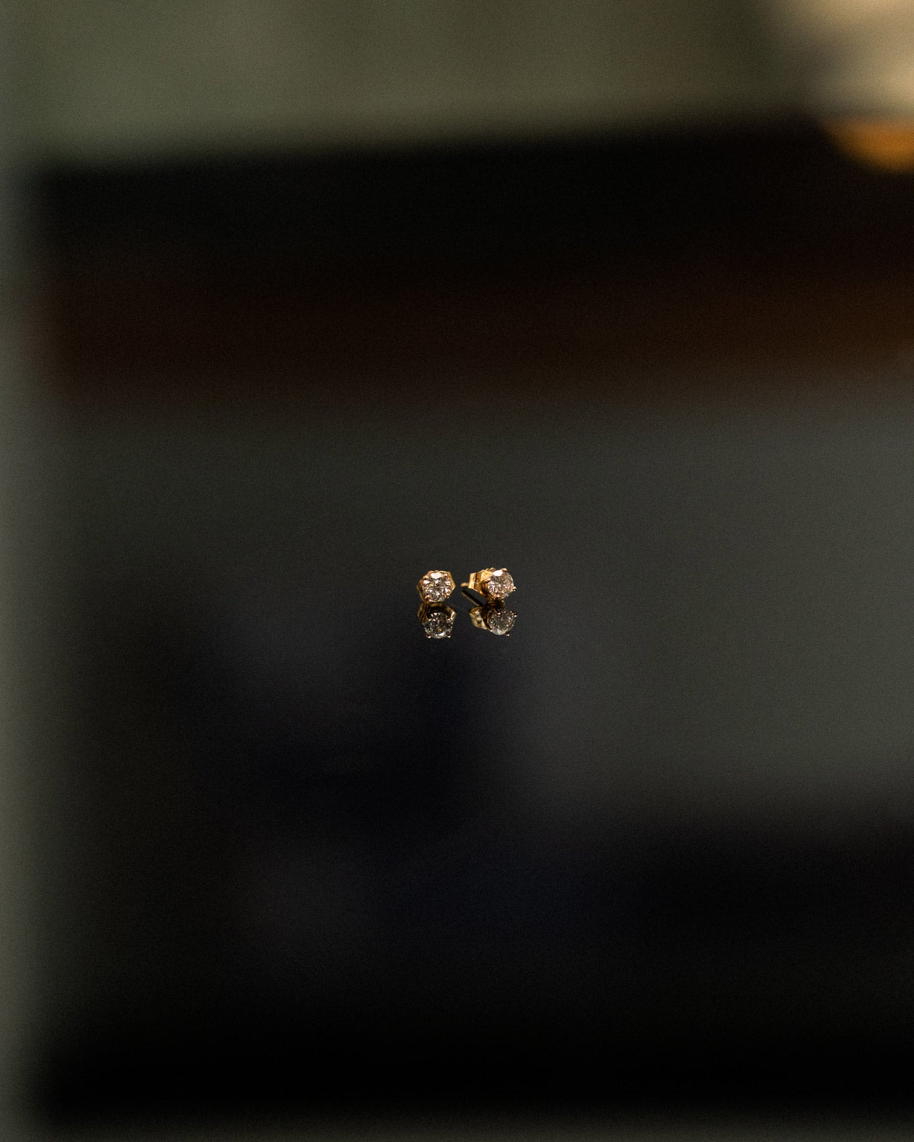 Single diamond stud earring on a dark background