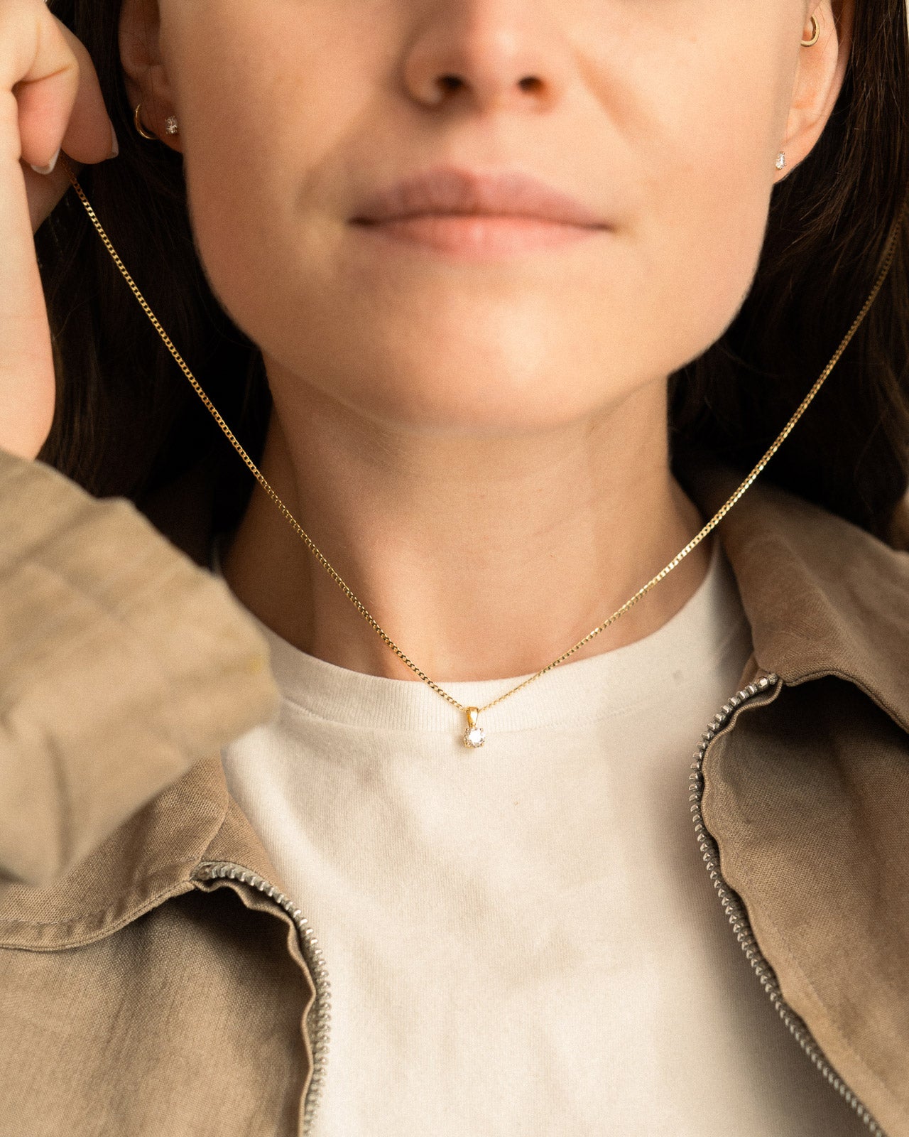 Close-up of a person wearing a gold necklace with a small pendant.