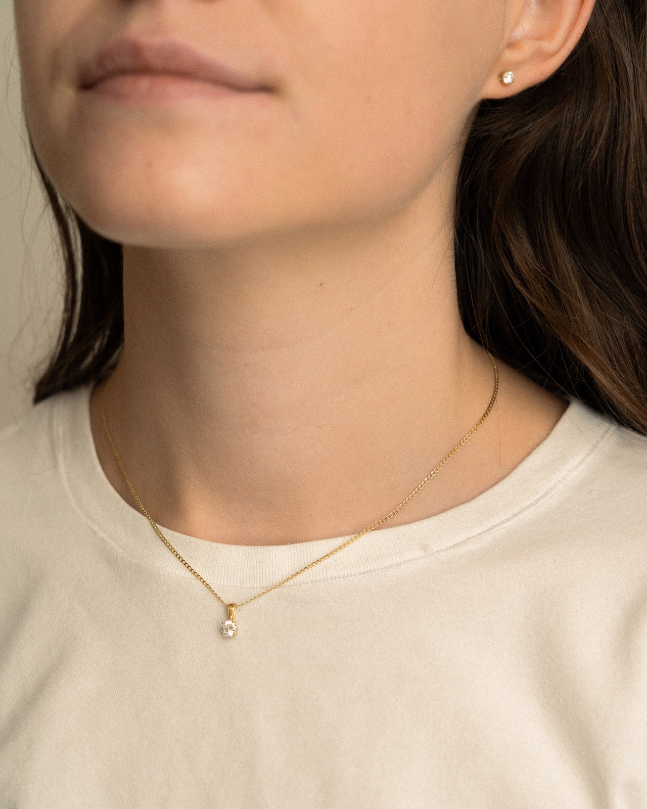 Close-up of a person wearing a gold necklace with a small pendant.