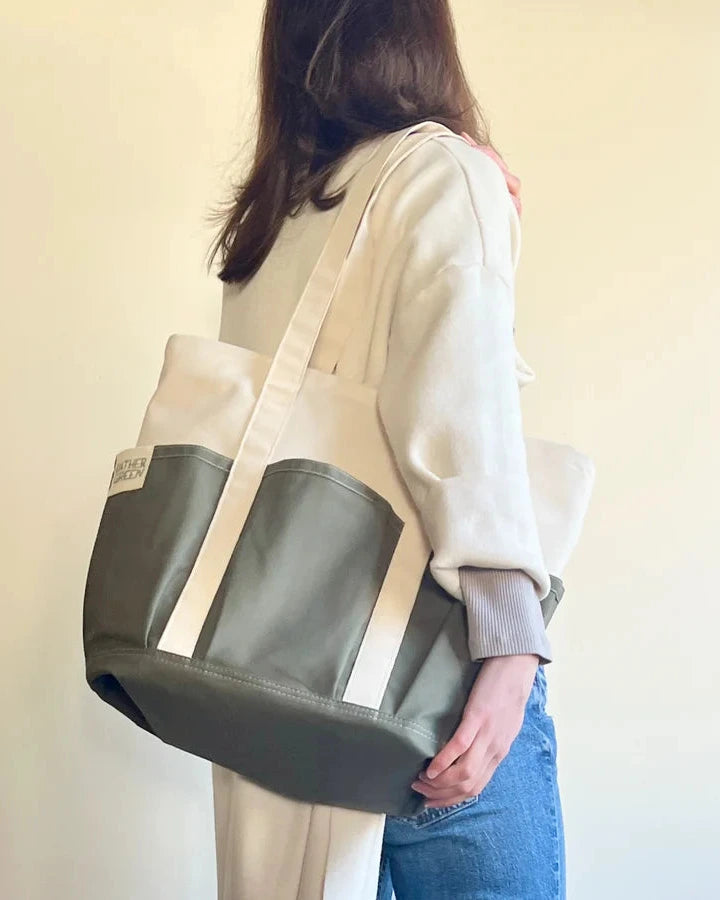 Person holding a two-toned Rather Green Amiga tote bag with a plain background