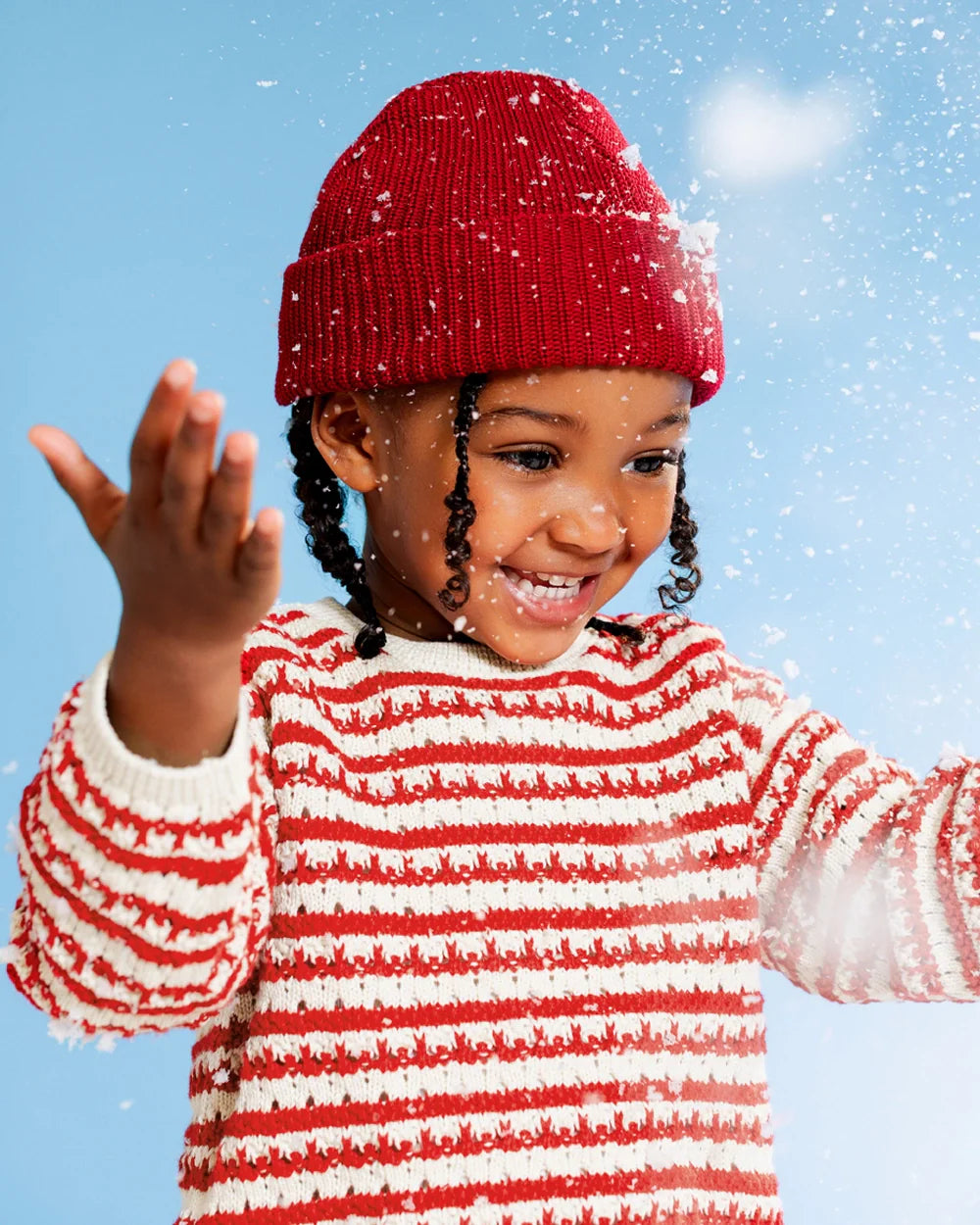 Child wearing a red and white striped sweater and red beanie in the snow