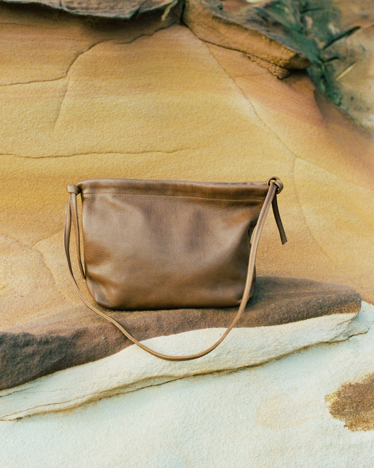 a brown leather handbag with a rocky background