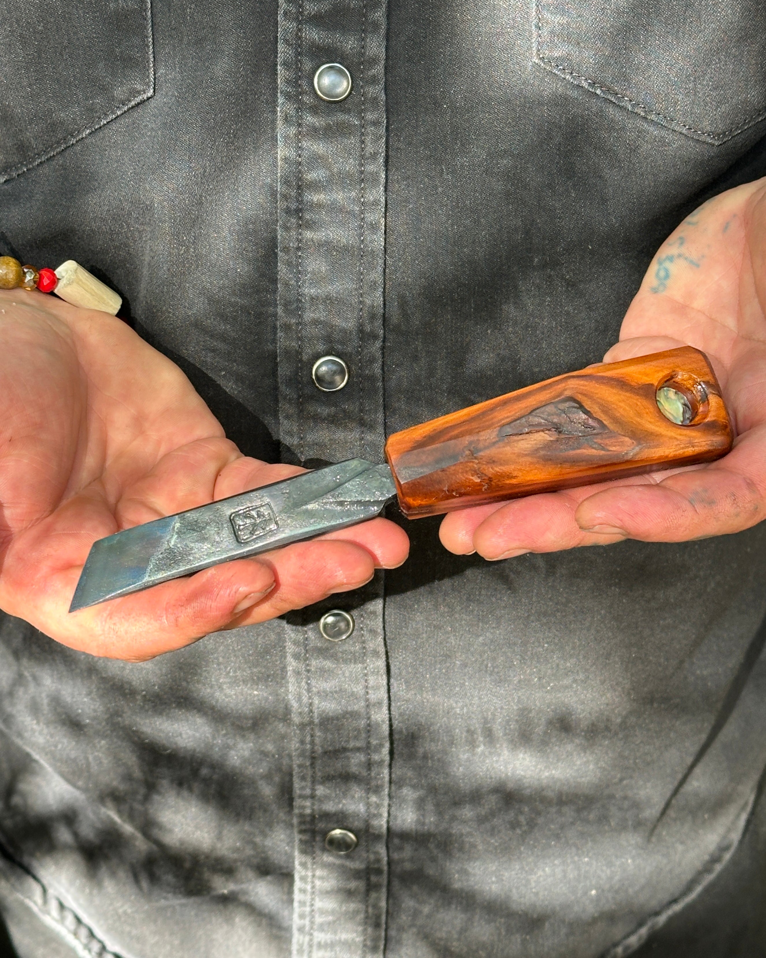 Person holding a shucker with a wooden handle and metal blade.