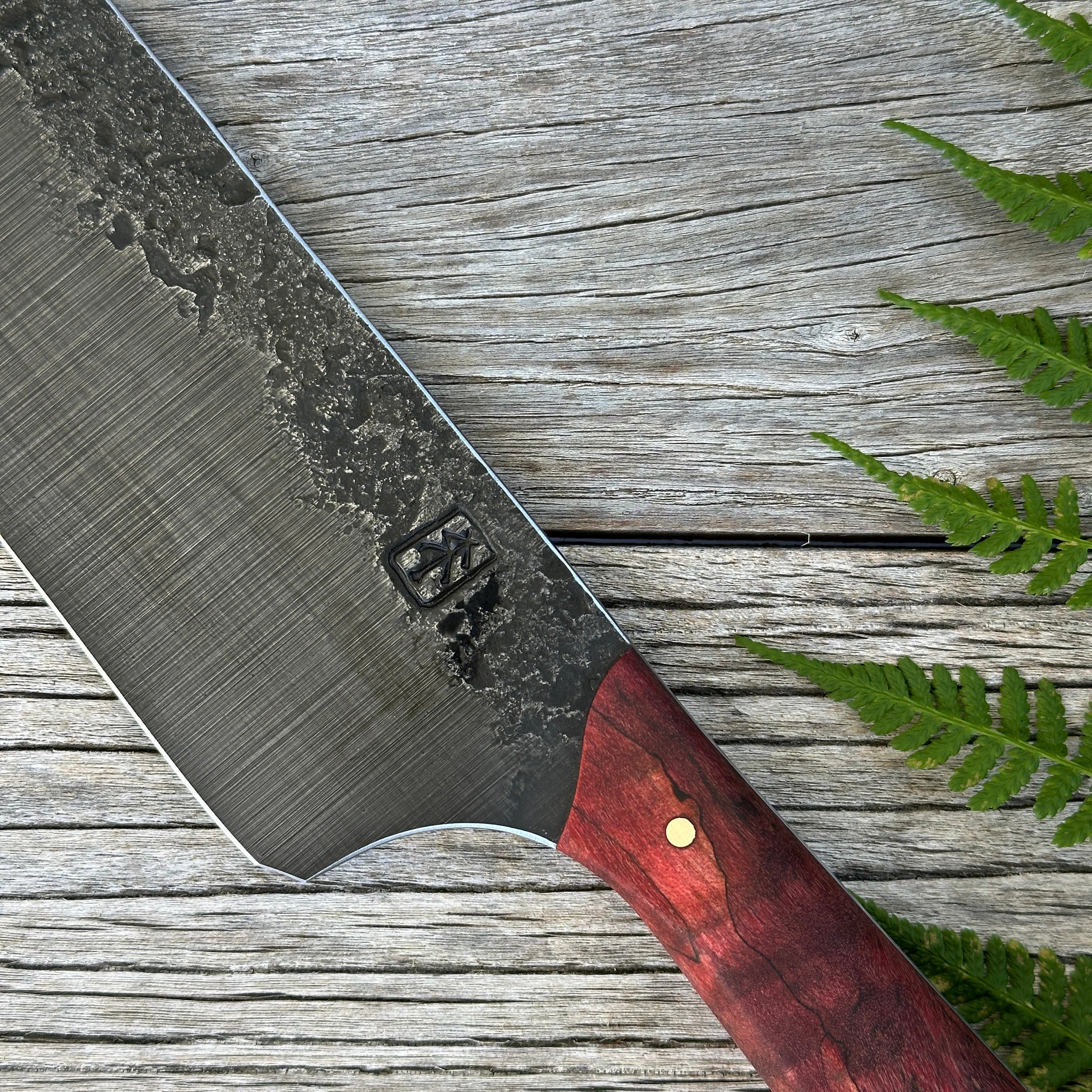 Leechtown Blacksmith Co. for Confluence Nimmo Bay knife with a wooden handle on a wooden surface with fern leaves