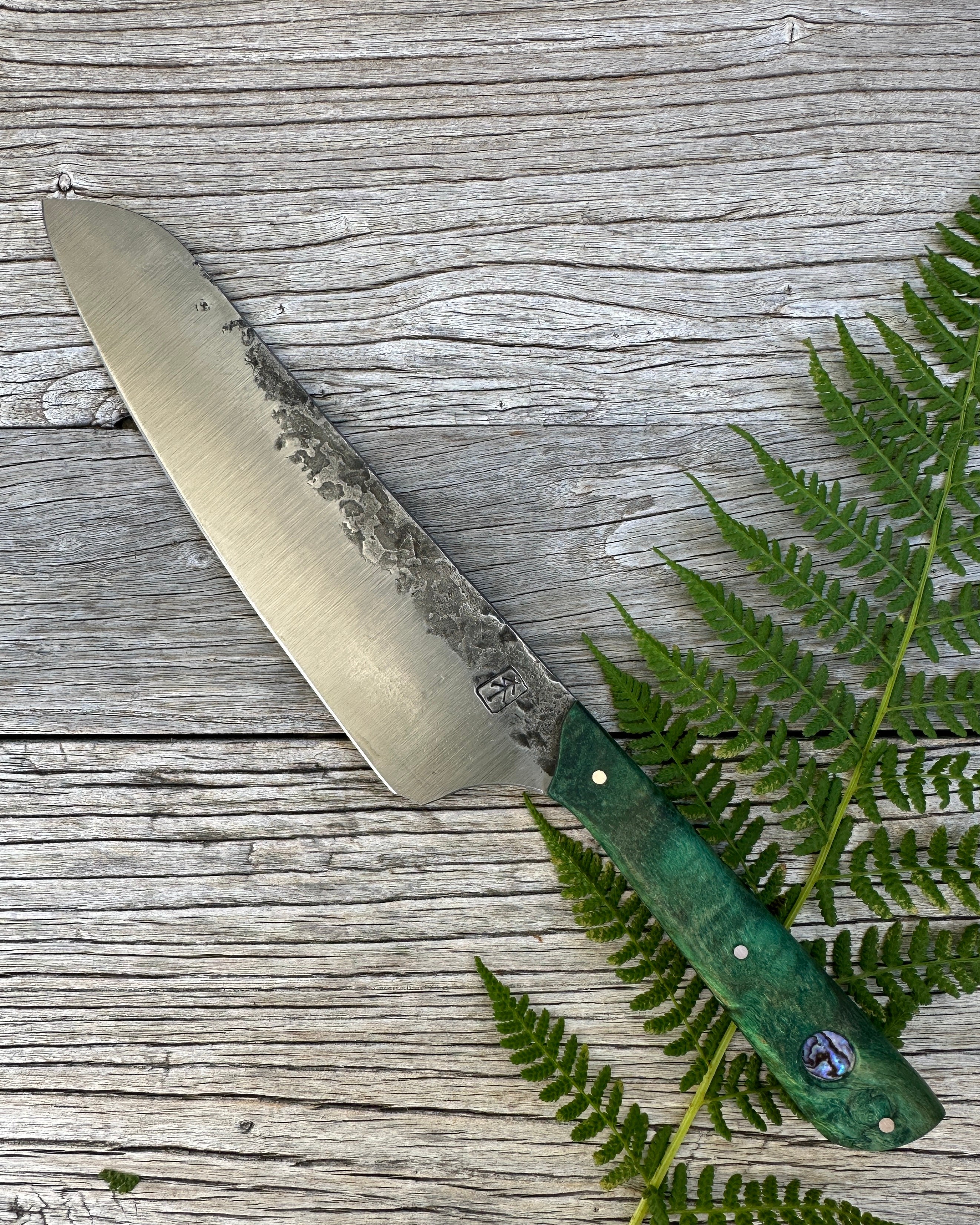 Leechtown Blacksmith Co. for Confluence Nimmo Bay knife with a green handle on a wooden surface with fern leaves