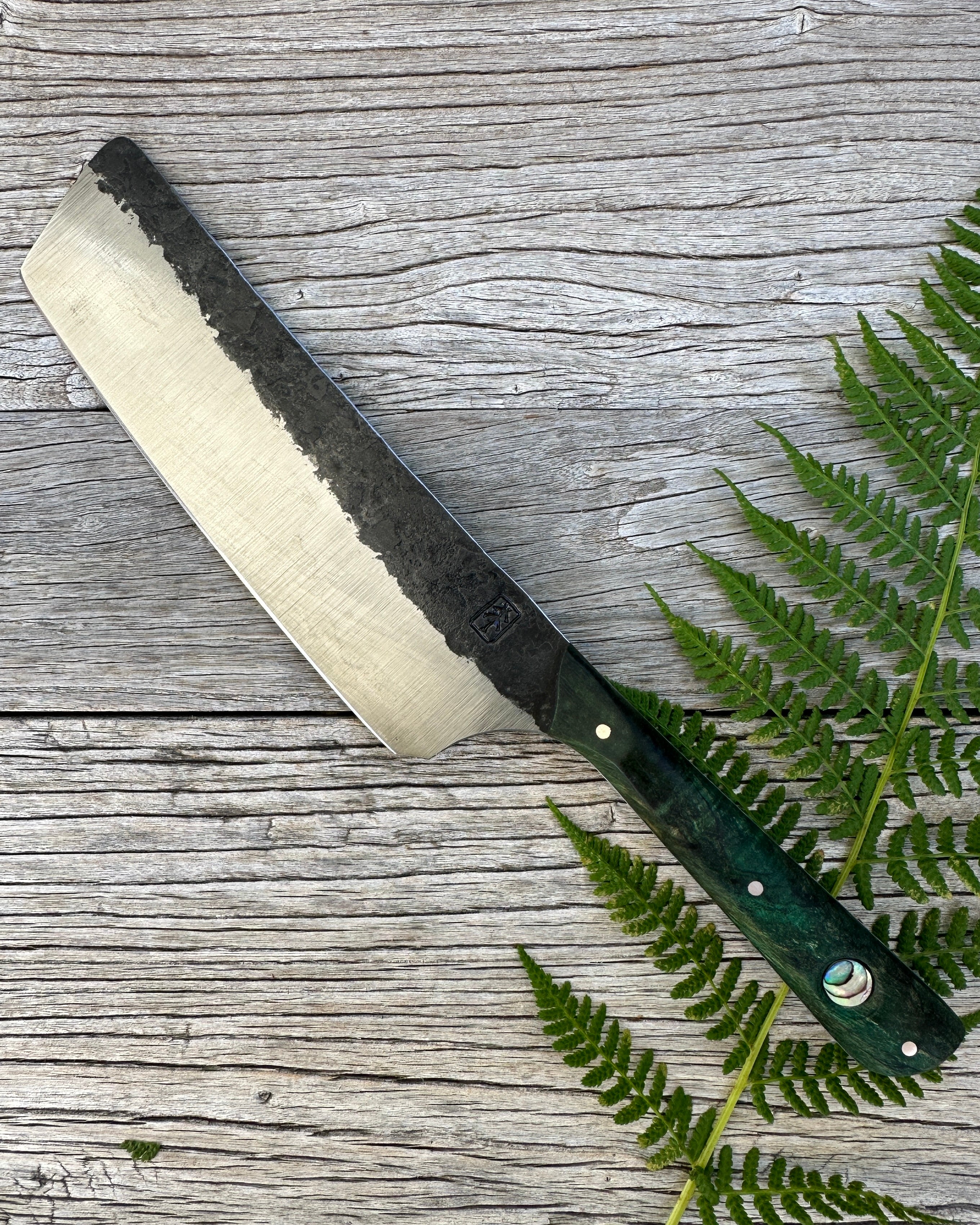Leechtown Blacksmith Co. for Confluence Nimmo Bay knife with a green handle on a wooden surface with fern leaves