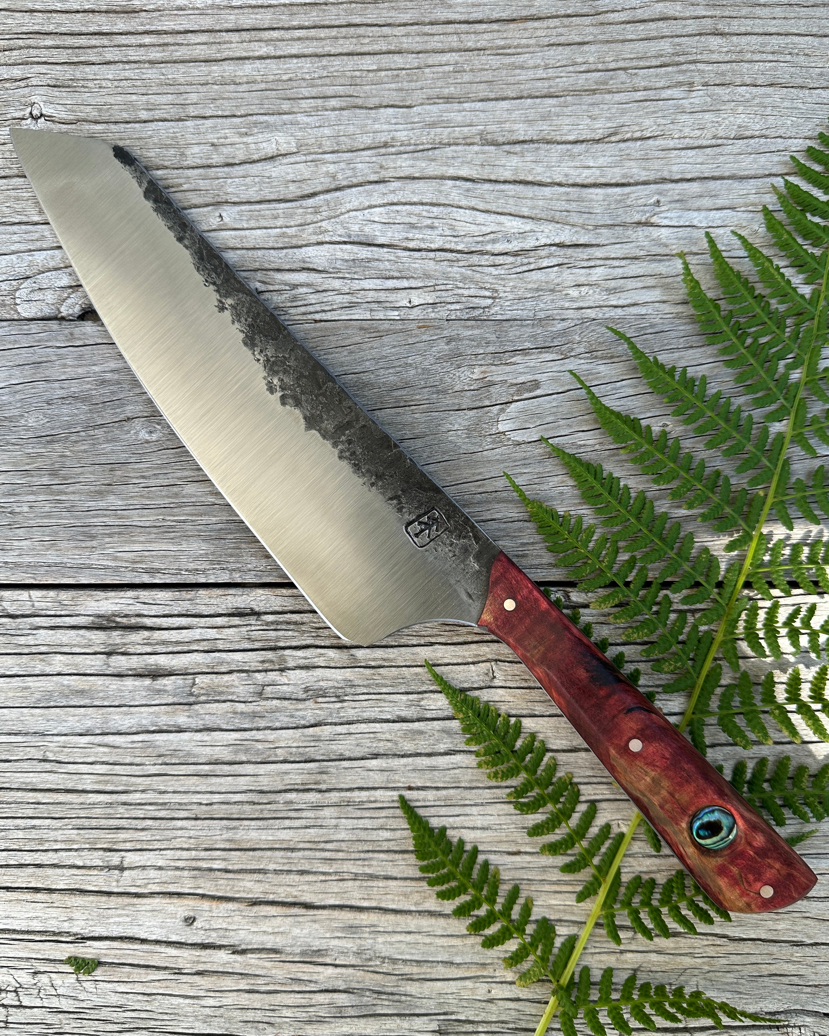 Leechtown Blacksmith Co. for Confluence Nimmo Bay knife with a natural wooden handle on a wooden surface with fern leaves