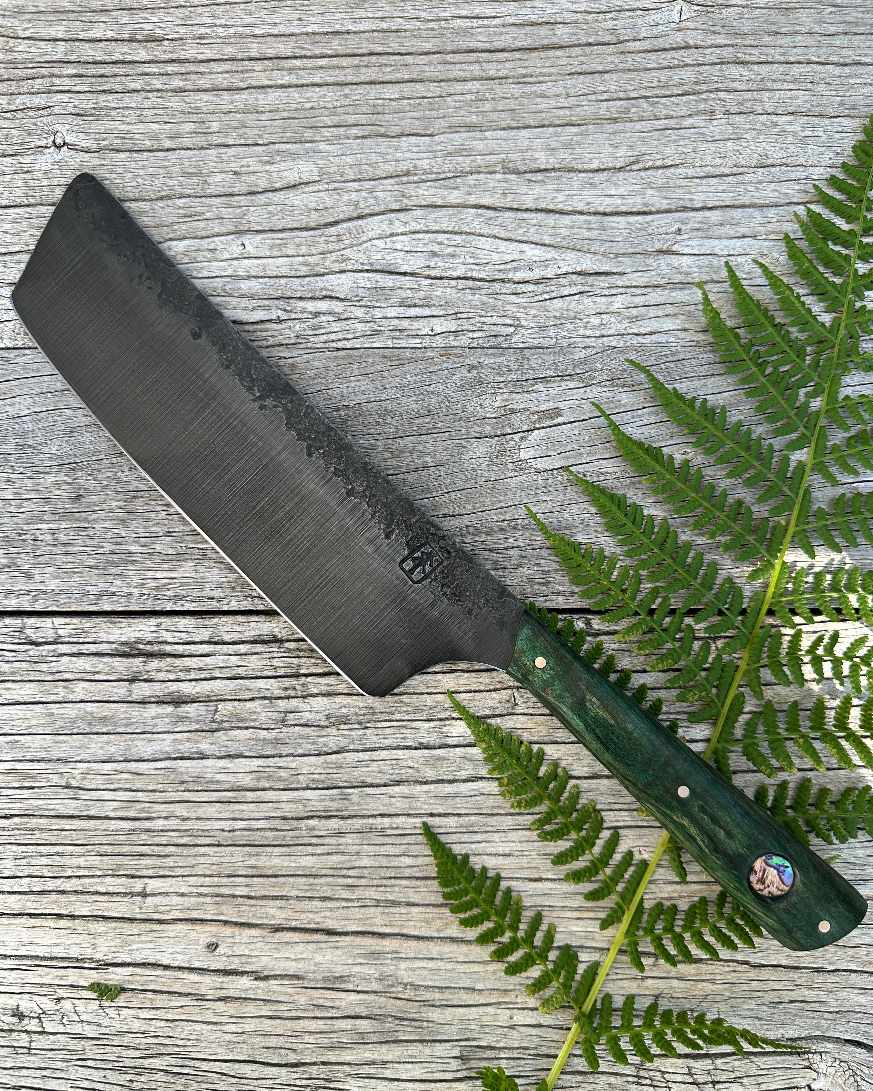 Leechtown Blacksmith Co. for Confluence Nimmo Bay knife with a green handle on a wooden surface with fern leaves