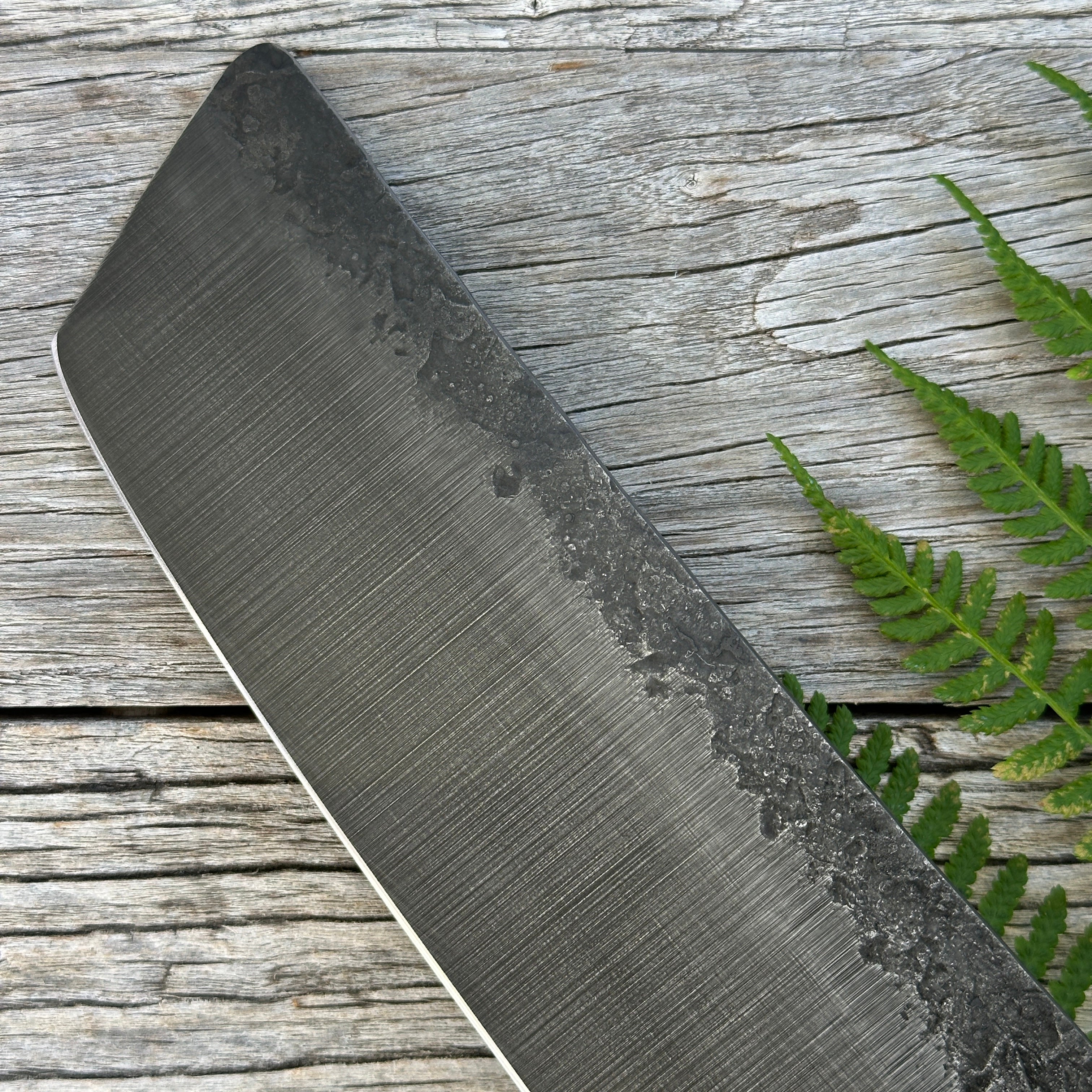Leechtown Blacksmith Co. for Confluence Nimmo Bay knife blade with textured surface on a wooden background