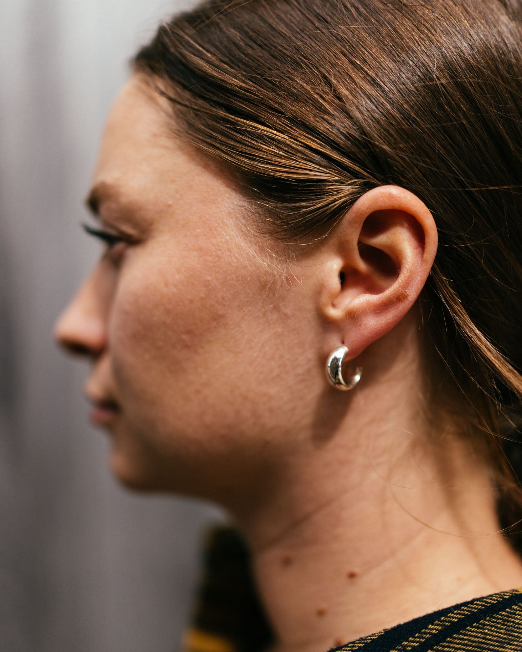 Close-up of a person wearing a silver earring with a blurred background