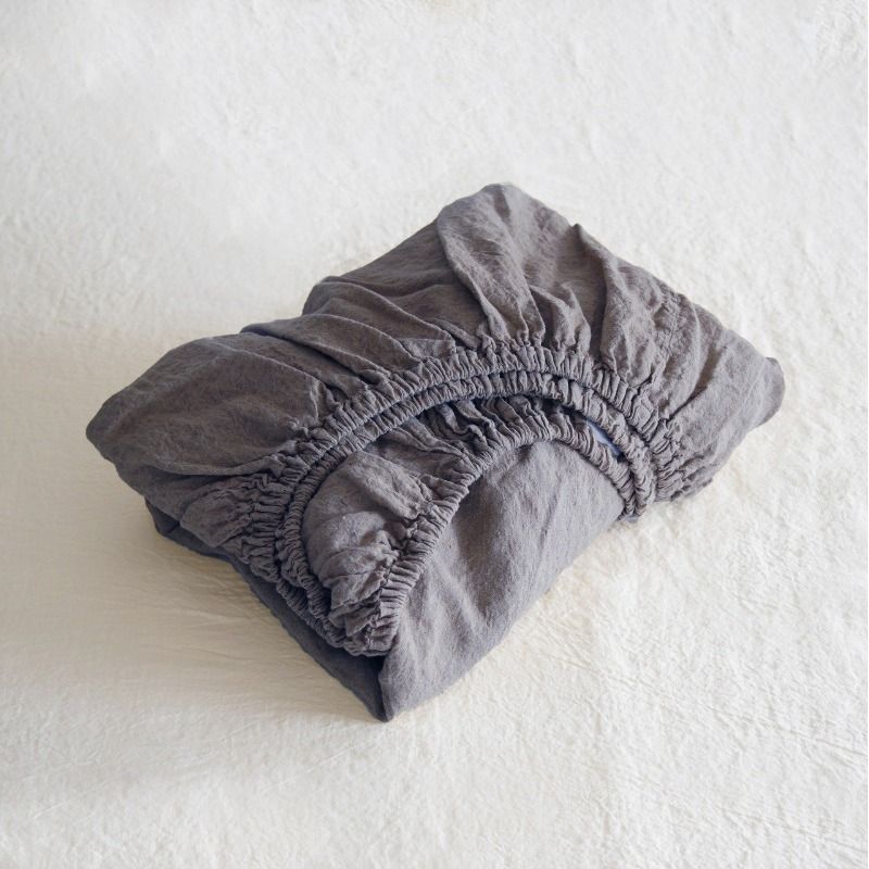 Folded gray fitted sheet on a white surface