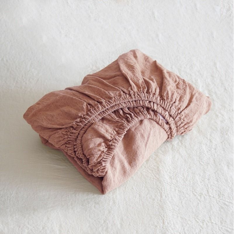 Folded pink fitted sheet on a white background
