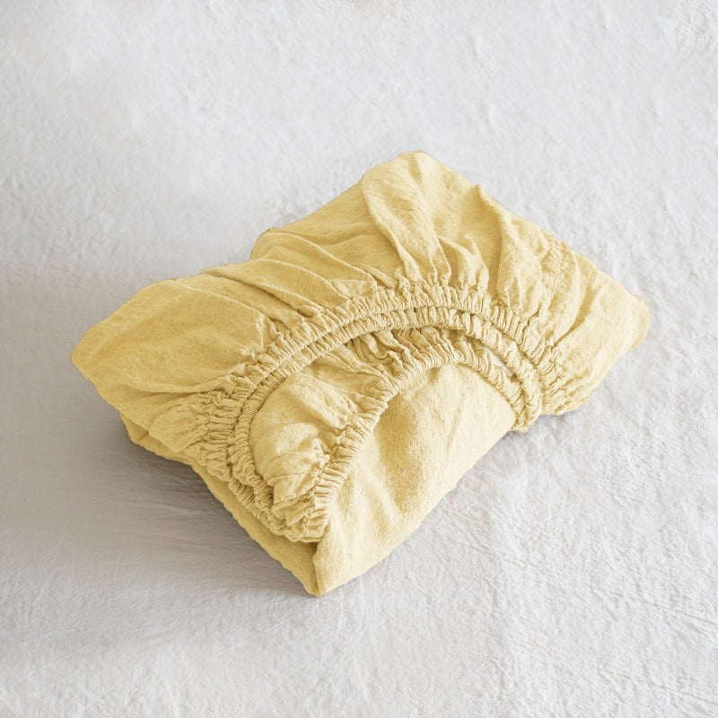 Yellow fabric fitted sheet on a white background