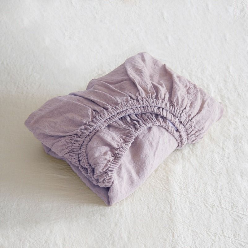 Folded lavender fitted sheet on a white surface