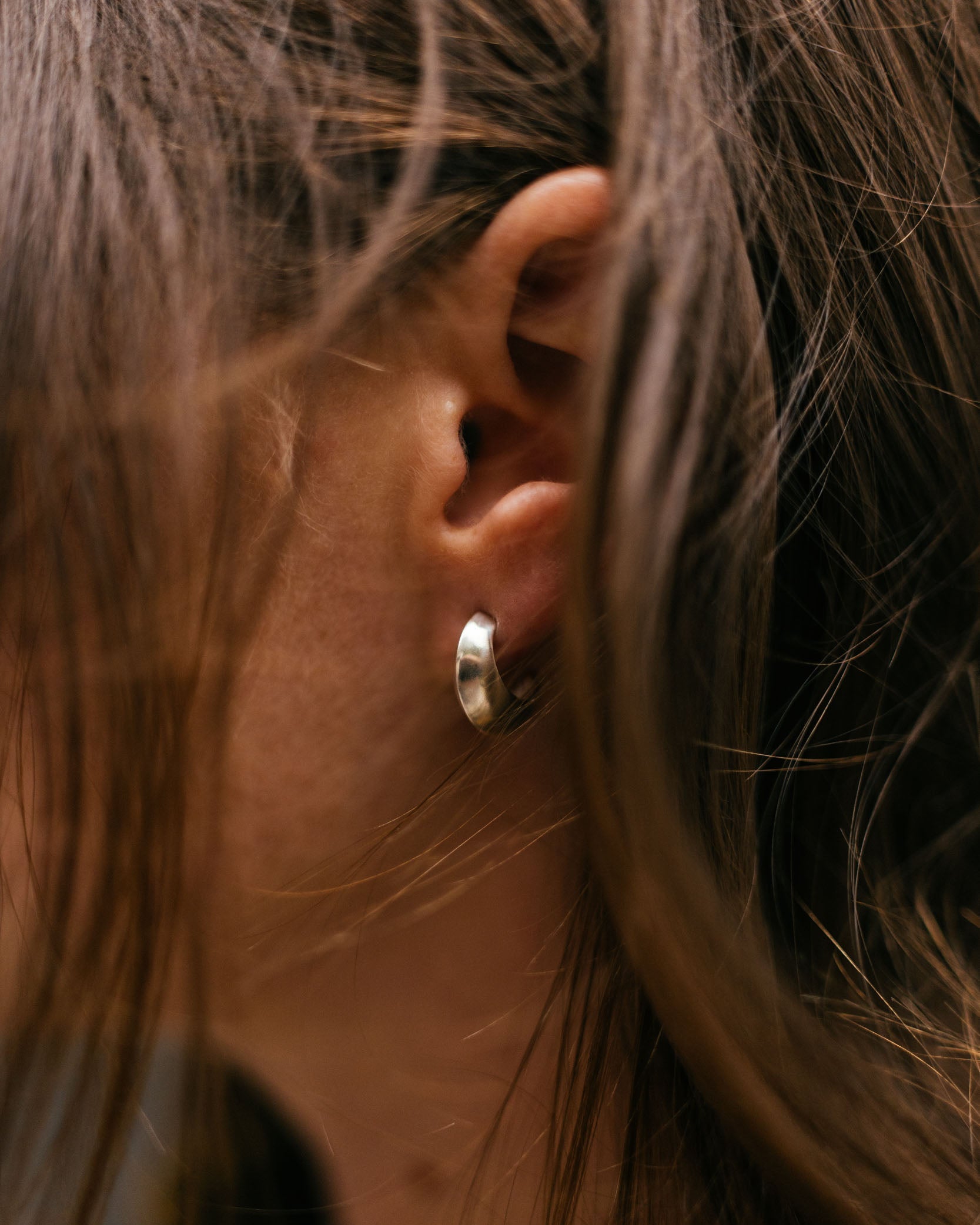 Close-up of an ear with a silver hoop earring