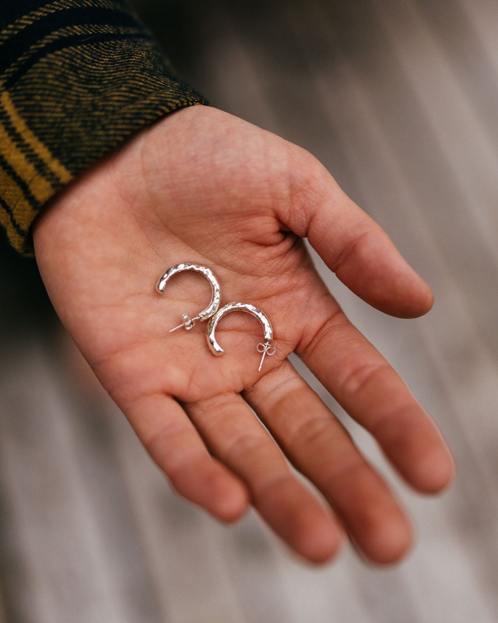 Hand holding two silver rings against a blurred background