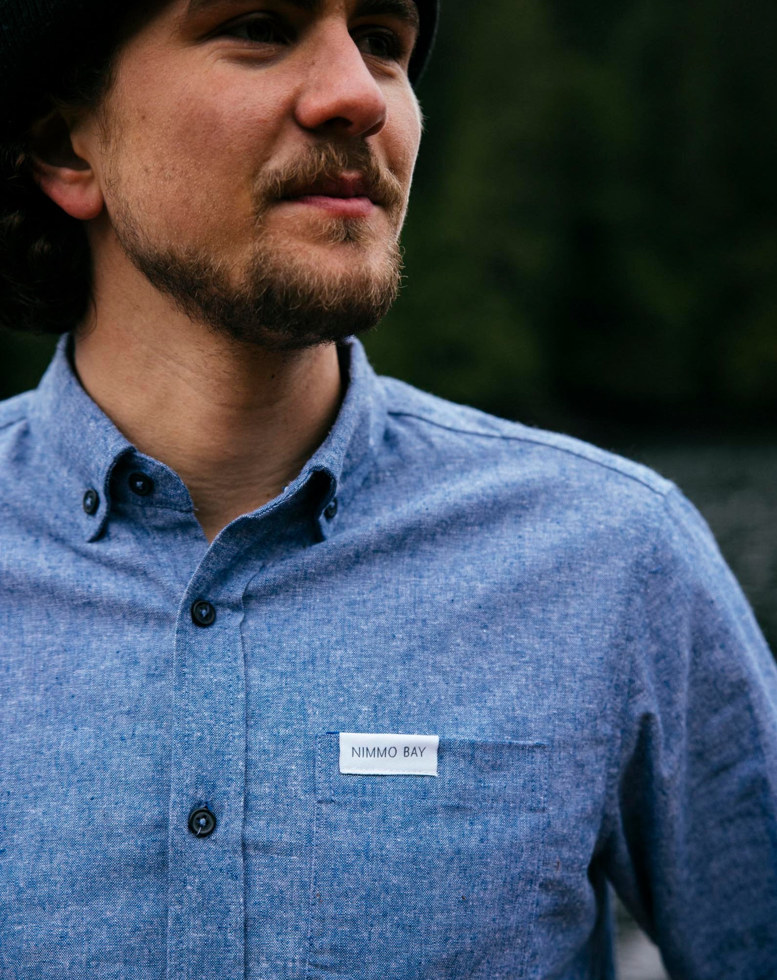 Nimmo Bay x Anian long sleeve blue chambray shirt. Man looking off into the distance