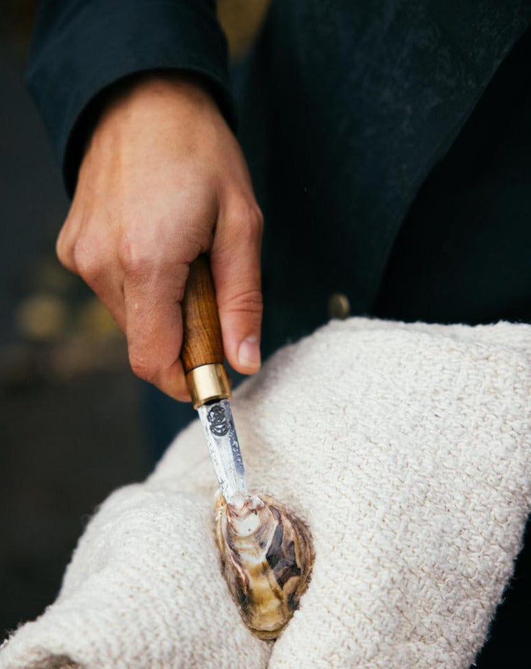 shucking an oyster with a handmade oyster shucker