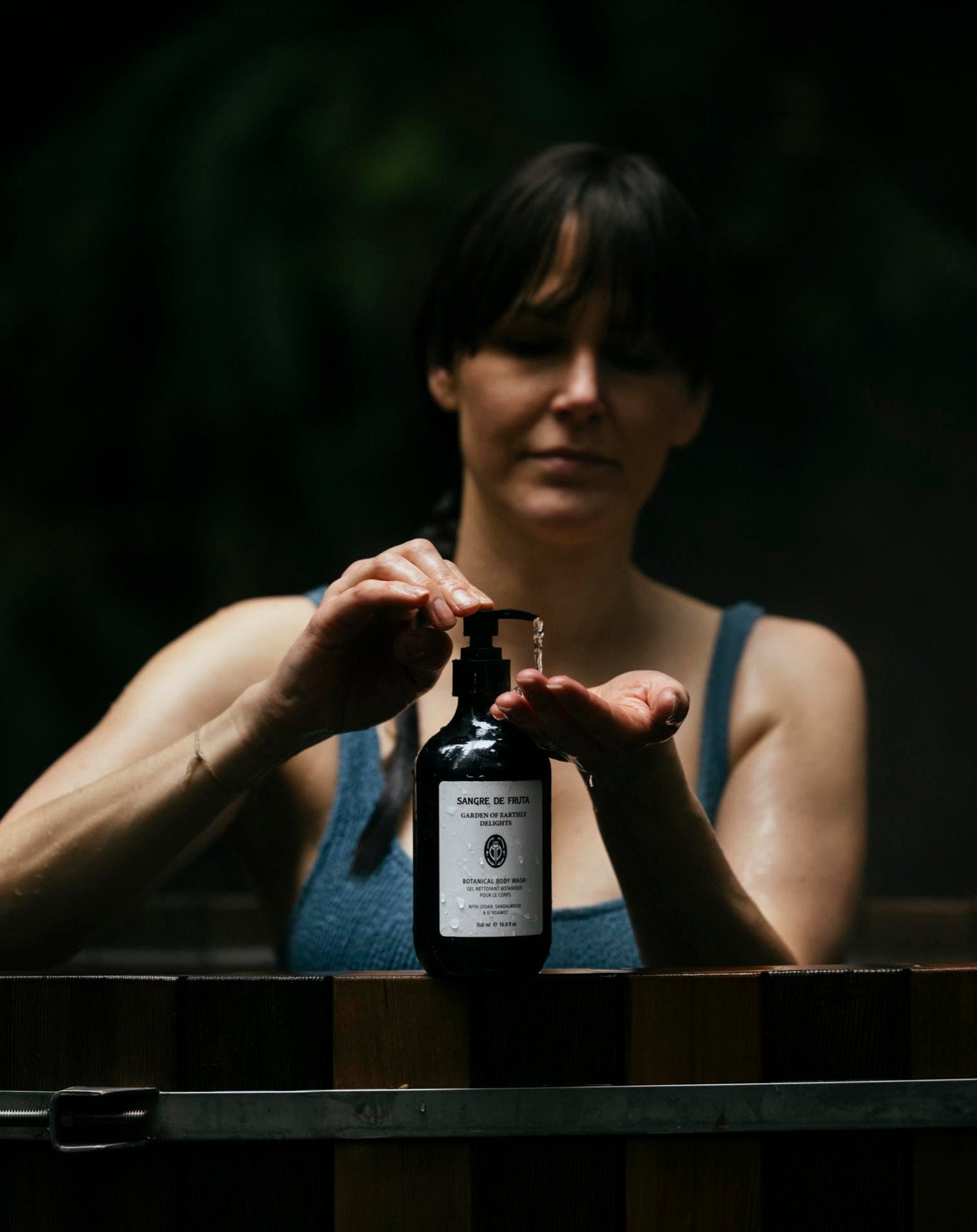 Woman usingn Sangre de Fruta body wash in an outdoor cedar tub