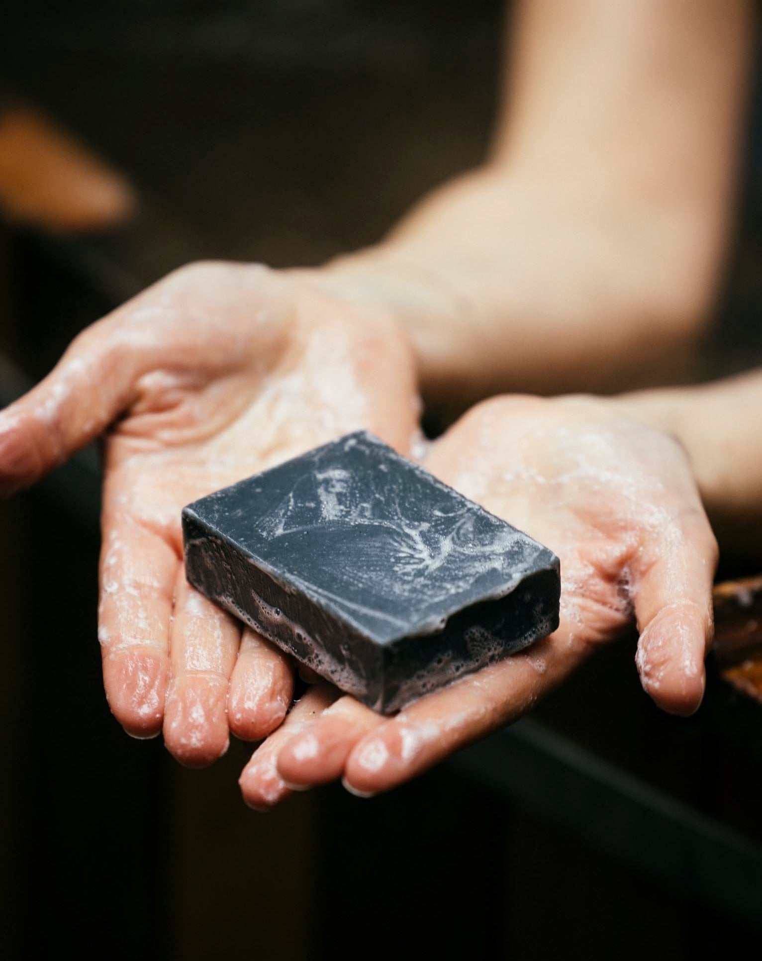 ALTR pine and charcoal soap lathered in a woman's hands